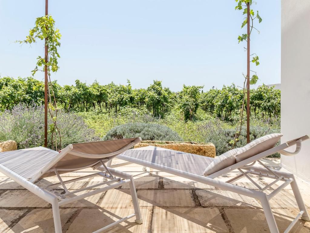 Una terrazza con due poltrone bianche e vista su un vigneto.
