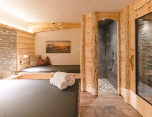 A wooden room with a bed, a bench, a shower, and a stone wall. - With 3 Bedrooms (Velturno)