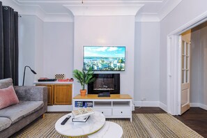 Een moderne woonkamer met een flatscreen televisie aan de muur, een bank, een salontafel en een open haard.