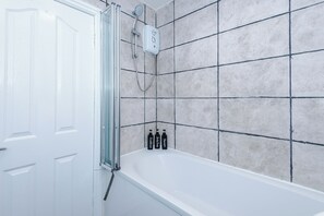Ein Badezimmer mit einer Badewanne, einer Dusche und einer gefliesten Wand.