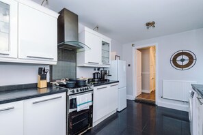 Een moderne keuken met witte keukenkastjes, een fornuis en een koffieapparaat.