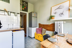 A compact kitchen with a refrigerator, a sink, and a dining area with a table and chairs. - Ikona Modernizmu w Stylu Boho (Poznań)