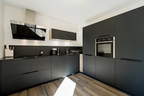 Eine moderne Küche mit dunklen Schränken, einem eingebauten Backofen und einer Mikrowelle.