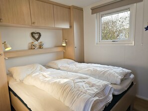 A bedroom with two beds, a window with a view, and a shelf with decorative items. - Se16 Serooskerke (Serooskerke)