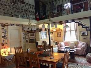 A cozy living room with a dining area, featuring a staircase, a sofa, and various decorations. - Holiday Apartment With 3 Bedrooms (Karlsborg)