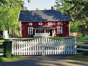 A red building with a white fence in front, a covered porch, and a clear sky. - Holiday Apartment With 3 Bedrooms (Karlsborg)