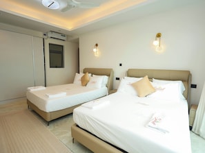 Ein Hotelzimmer mit zwei Betten, einem Deckenventilator, einer Klimaanlage und Wandleuchten.
