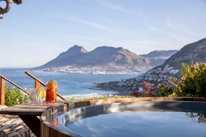 Un área de piscina con vistas a las montañas y al océano.