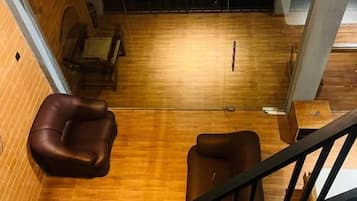 A wooden-floored room with a staircase, a brown leather chair, and a small table.
