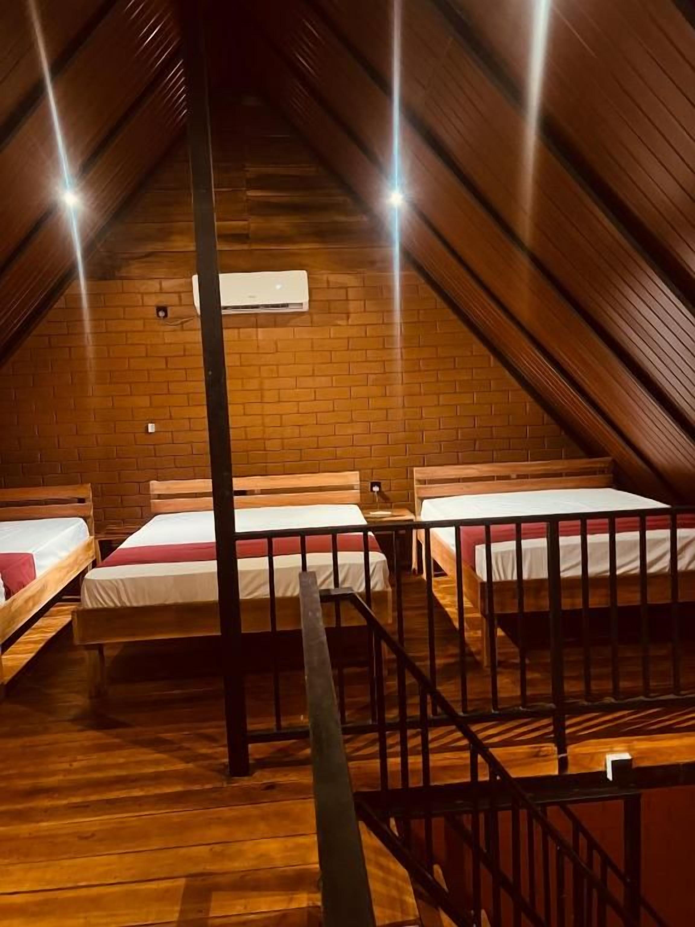 Een slaapzaal met stapelbedden, een bakstenen muur en een airconditioner.