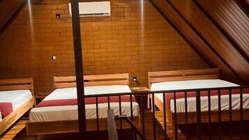 Een slaapzaal met stapelbedden, een bakstenen muur en een airconditioner.