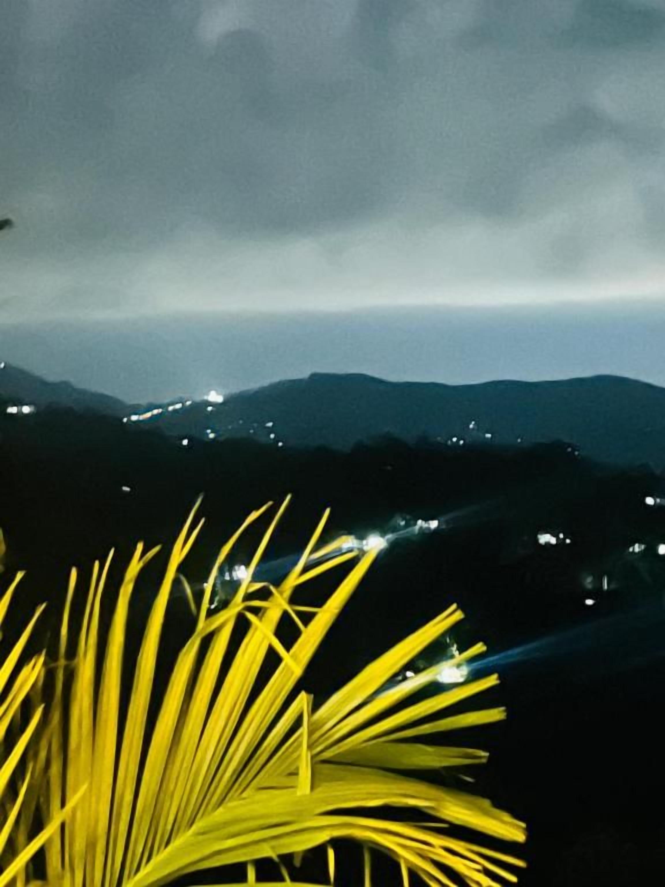 Vista nocturna de un paisaje montañoso con luces distantes.