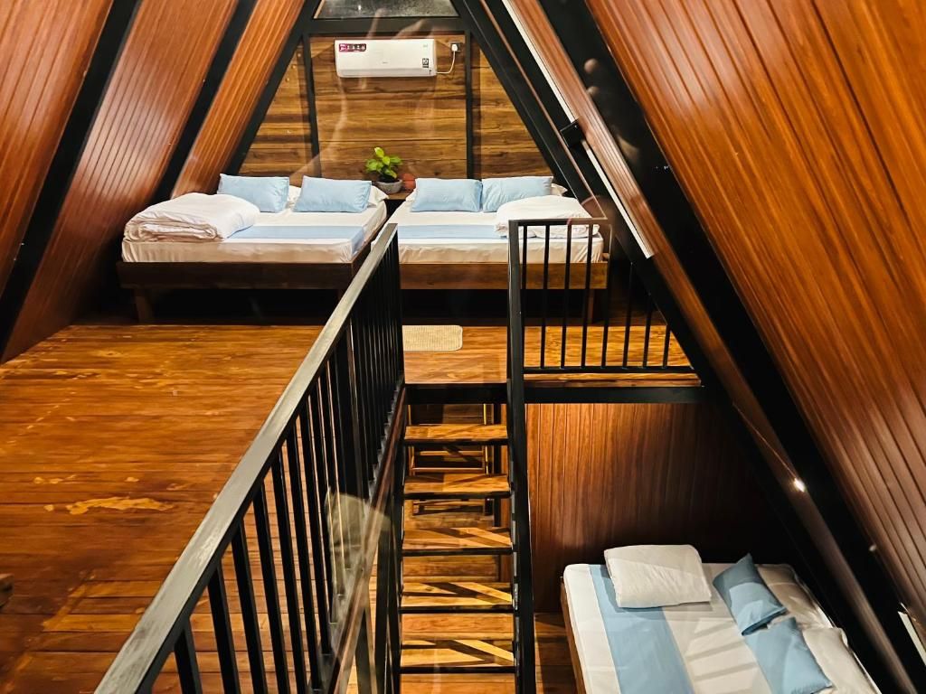 Un dormitorio estilo altillo triangular con literas, piso de madera y una pequeña mesa con una planta.
