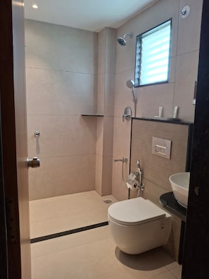 A modern bathroom with a shower, toilet, and a window. - SRS Elegance (Bengaluru)
