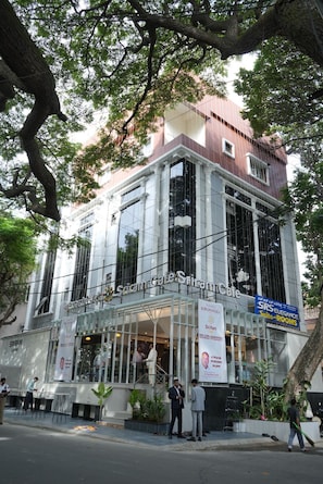 A building with a cafe named 'Sri Ram Cafe' on the ground floor, featuring large windows and a modern architectural design. - SRS Elegance (Bengaluru)