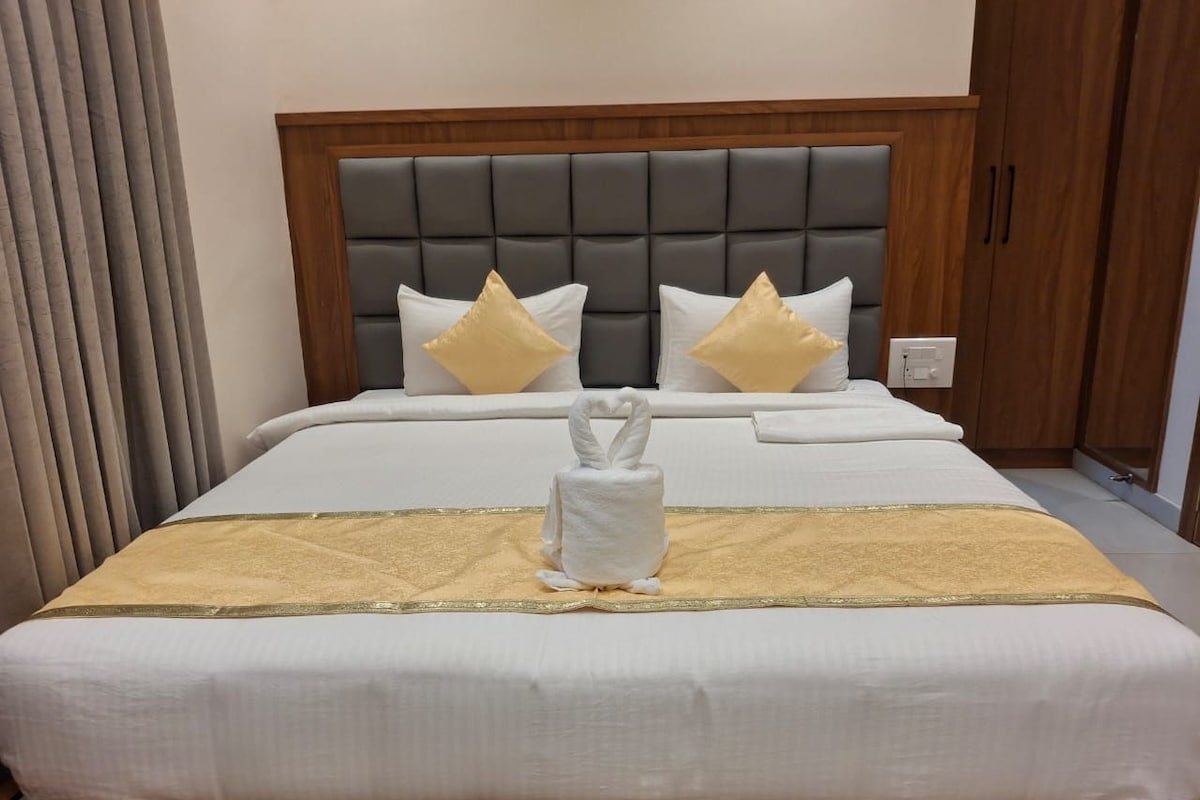 A hotel room with a large bed, a wooden headboard, and a white towel centerpiece.