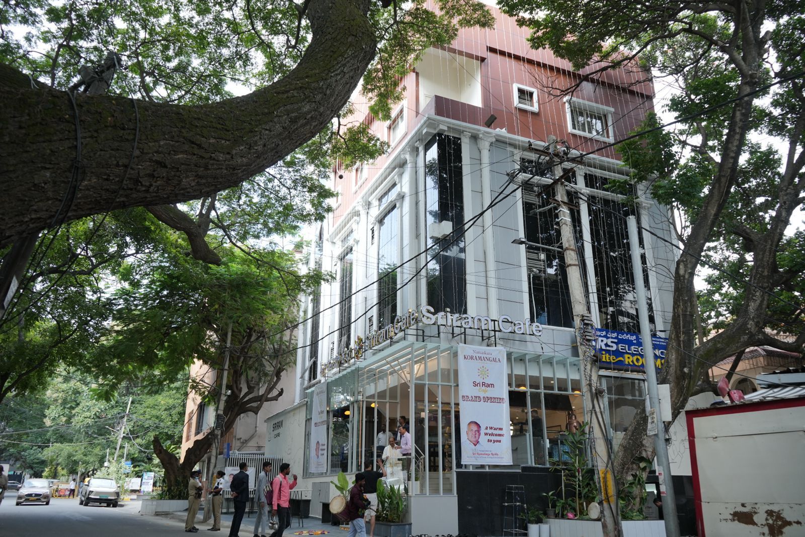 A building with a storefront labeled 'Sri Ram Cafe' and a signboard for 'Koramangala Sri Ram.'