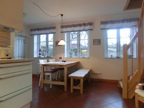A kitchen with a wooden table, chairs, a bench, and a hanging light fixture. - Holiday Apartment With 1 Bedroom (Steinbergkirche)