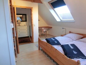 A bedroom with a skylight, a wooden bed, and a desk. - Holiday Apartment With 1 Bedroom (Steinbergkirche)