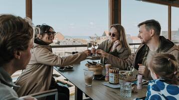 Un grupo de personas brindando con bebidas en una mesa con vista al mar.
