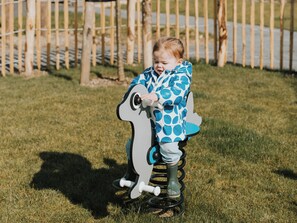 A child on a swing set in a grassy area with a wooden fence in the background. - Enjoying each other and the oyster culture in Yerseke, Zeeland (Yerseke)