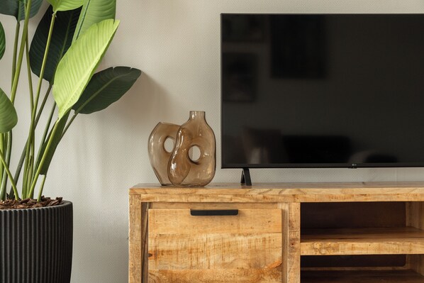 A wooden TV stand with a flat-screen TV, a decorative vase, and a potted plant. - Go out and discover the oyster culture in Yerseke together! (Yerseke)