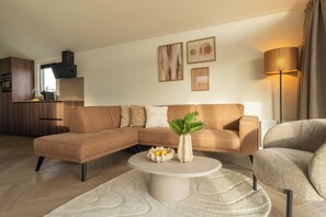 Ein modernes Wohnzimmer mit einer Eckcouch, einem runden Couchtisch und einer Stehlampe.