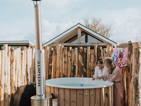 A wooden fence, a hot tub, and a person leaning over the tub.