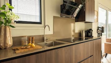 A modern kitchen with a built-in sink, wooden cabinets, a window with blinds, and a potted plant.