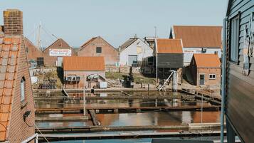 A view of a riverside area with buildings, including a brick structure with a sign that reads 'PIET VAN BOOST.'