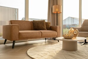 Ein modernes Wohnzimmer mit einem braunen Sofa, einem runden Couchtisch und einer Lampe.