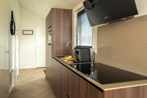 Una cucina moderna con piano cottura integrato, una macchina da caffè e una finestra con persiane.