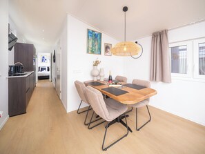 Een moderne eetruimte met een houten tafel, beklede stoelen en een hangende lamp.