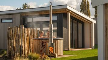 Un sauna extérieur moderne, doté d’une structure en bois et d’un foyer visible à l’intérieur.