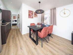 Una camera d'albergo moderna con zona pranzo, angolo cottura e un'ampia finestra con tende.