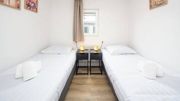 Une chambre double avec deux lits, une petite table et une fenêtre avec des rideaux.