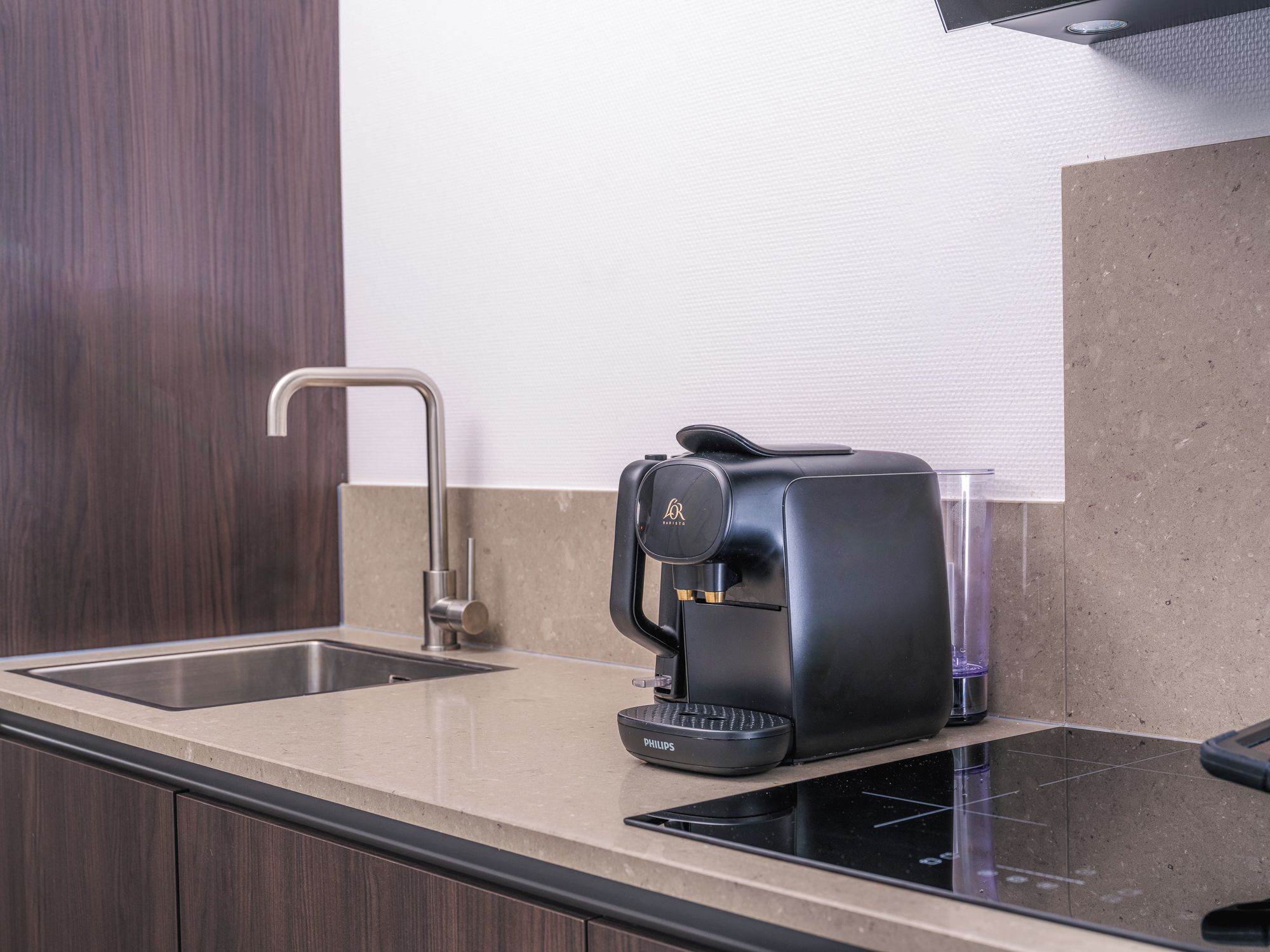 Une cuisine moderne équipée d’une machine à café intégrée, d’un évier et d’un plan de travail.