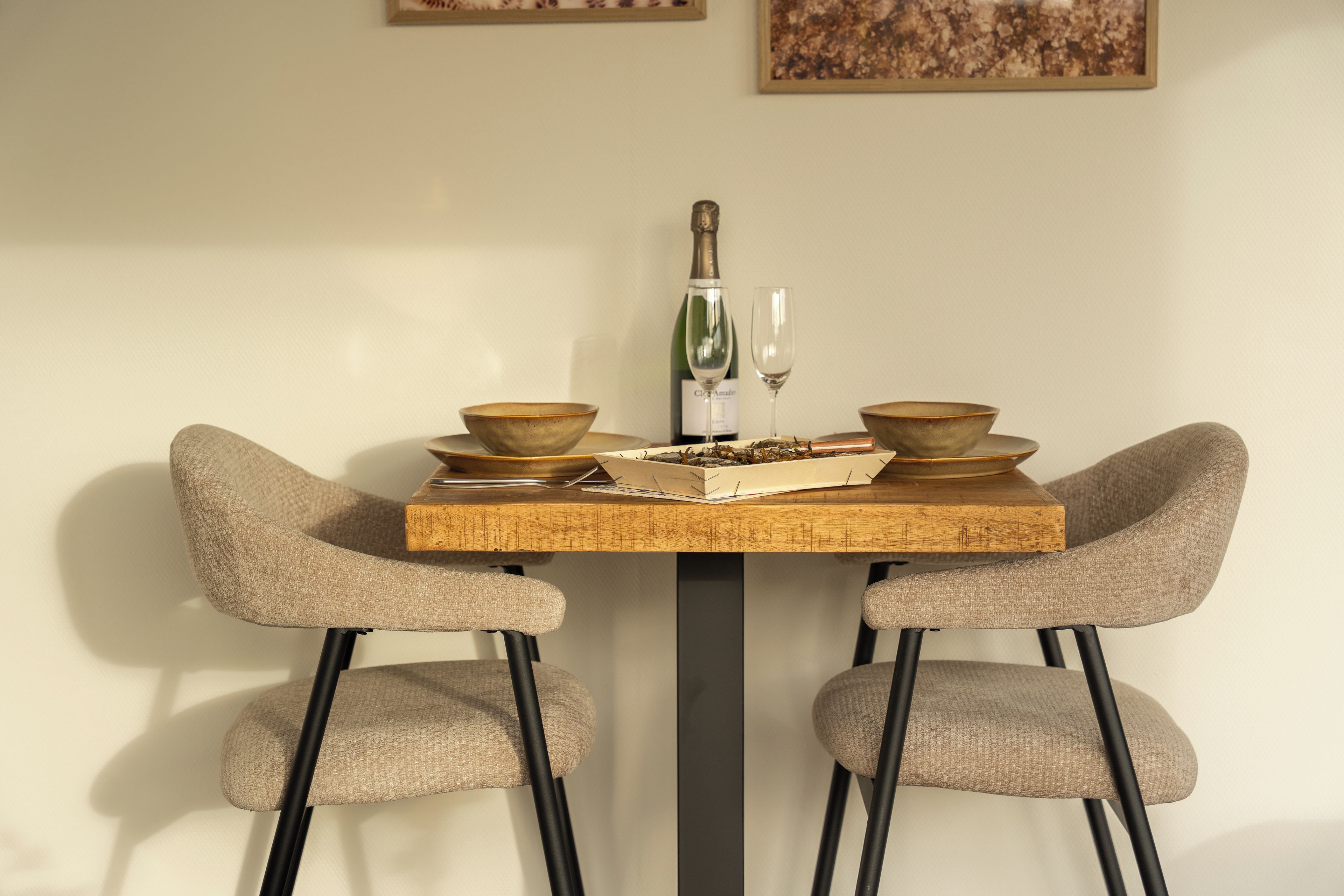 Una mesa de comedor con dos sillas, una botella y dos cuencos.