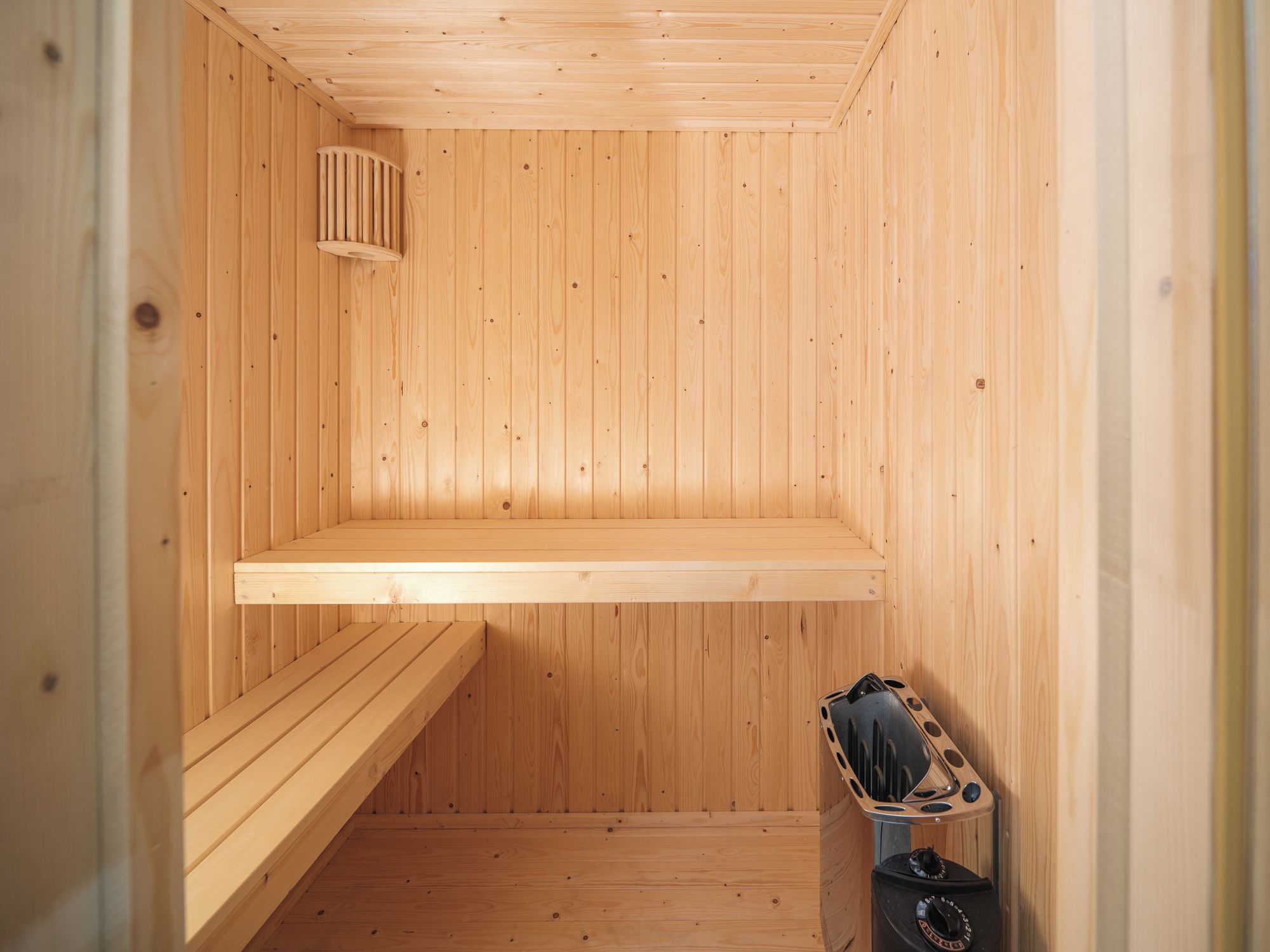 Un sauna en bois, avec un banc et un réchauffeur de sauna.
