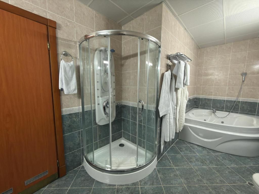 A bathroom with a glass-enclosed shower, a bathtub, and a wooden door.