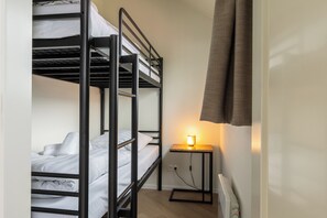Ein Schlafraum mit Etagenbett, Nachttisch und Lampe.