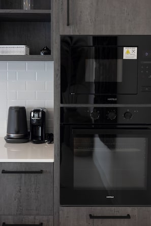 Una cucina con un forno nero Hafele, una macchina da caffè e un microonde sul piano di lavoro.