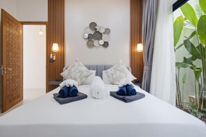 Ein Hotelzimmer mit einem Bett, zwei Kissen, einer Wandleuchte und einer Tür.