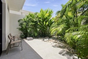 Un cortile con un’area salotto, palme e pavimento piastrellato.