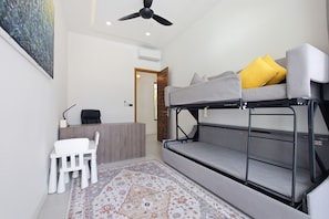 Una stanza compatta con un letto a castello, una scrivania, una sedia e un tappeto decorato.