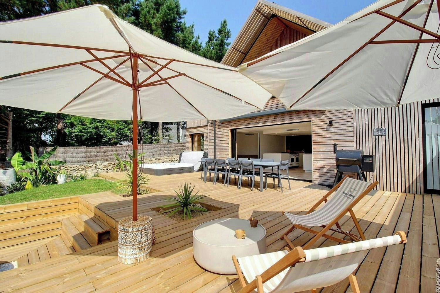 Une terrasse extérieure comprenant un espace repas, des chaises longues et un barbecue.
