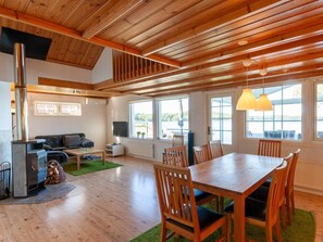 A spacious room with a wooden ceiling, a dining table with chairs, a sofa, and a fireplace. - Holiday Home With 3 Bedrooms (Ambjörnarp)