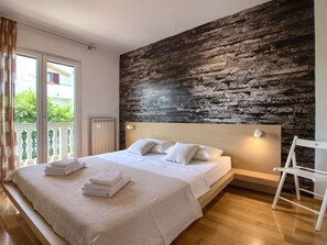 A bedroom with a bed, a radiator, a balcony, and a white chair. - Villa Magnifica With Private Pool in Pula (Pula)