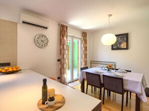 A dining area with a table set for two, a clock on the wall, and a window with curtains. - Villa Magnifica With Private Pool in Pula (Pula)