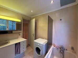 A modern bathroom with a washing machine, a bathtub, and a large mirror. - Apartment with balcony and ski slopes view (Les Deux Alpes)
